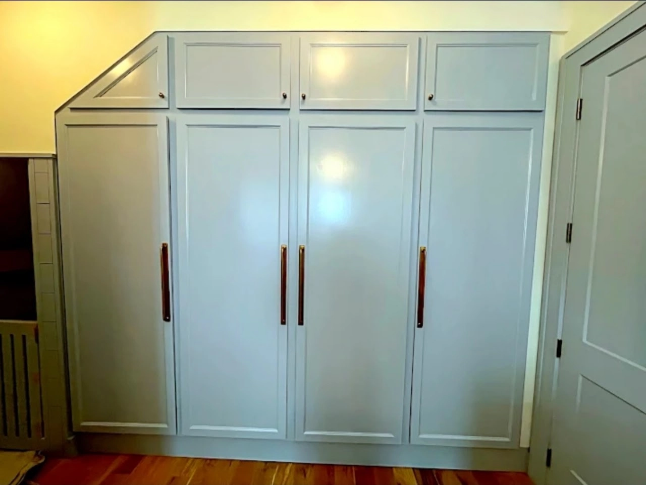 Built-in wardrobe fitted to angled ceiling with brass hardware